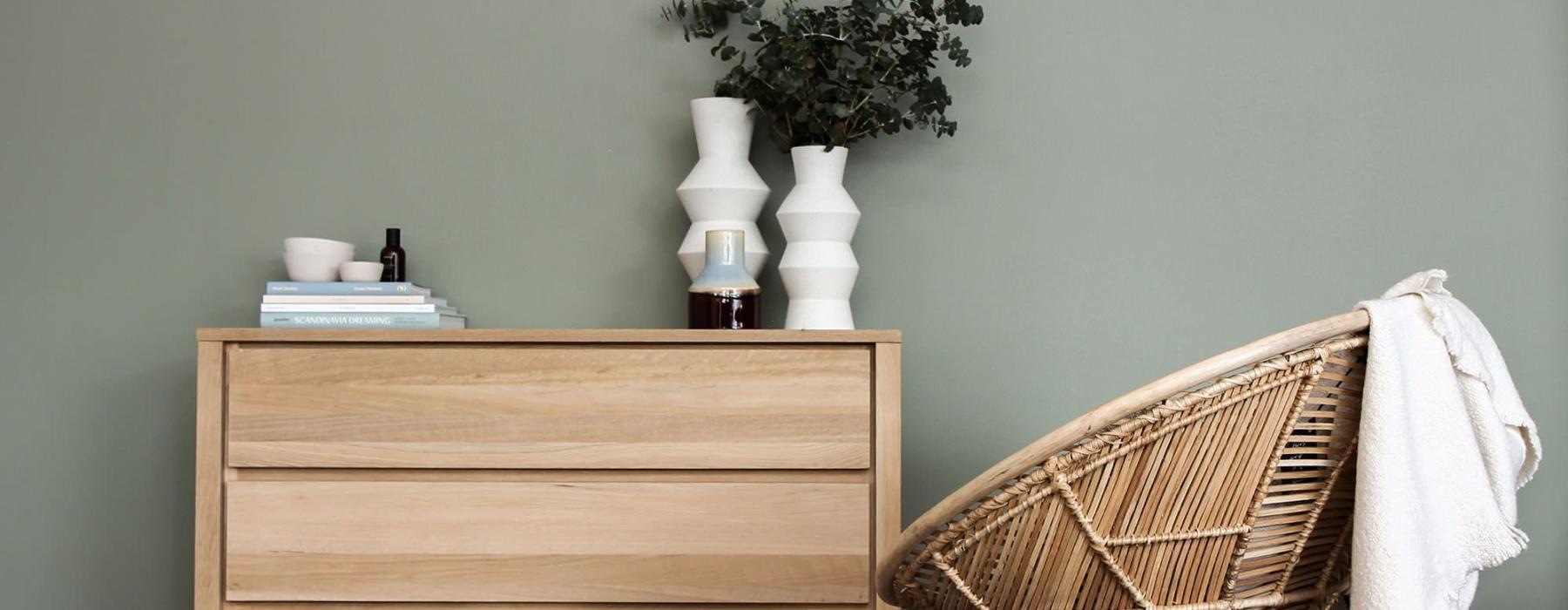 decor on a tall, wooden dresser next to a papasan chair with a throw