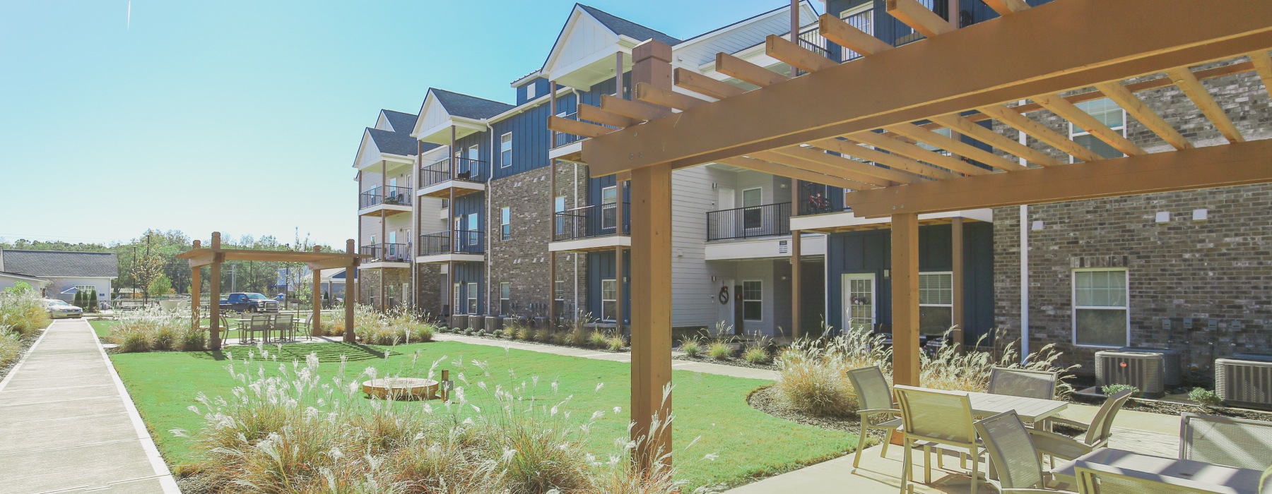 Pergolas with seating areas in front of apartment buildings
