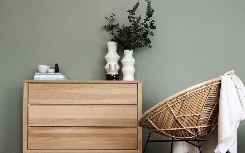 decor on a tall, wooden dresser next to a papasan chair with a throw