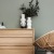 decor on a tall, wooden dresser next to a papasan chair with a throw