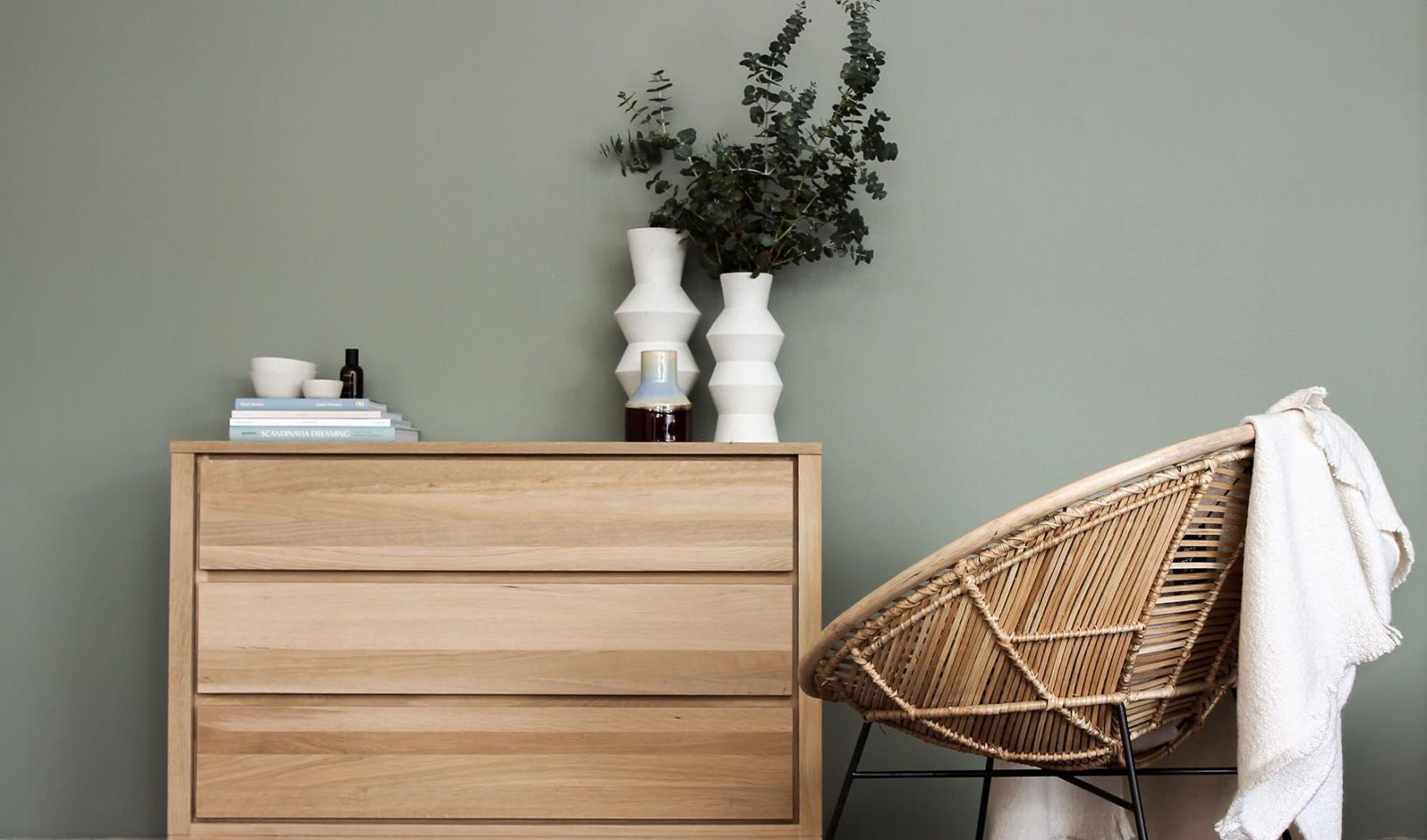 decor on a tall, wooden dresser next to a papasan chair with a throw